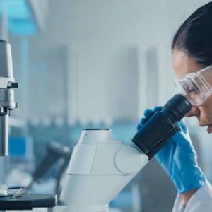 A female scientist looking through a miscroscope in a laboratory.